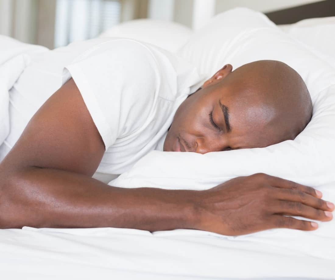 man laying on his stomach in bed, peacefully