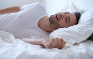 young adult man snoring in bed